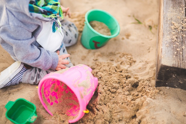 kid playing in sand with buckets - free summer stock photo